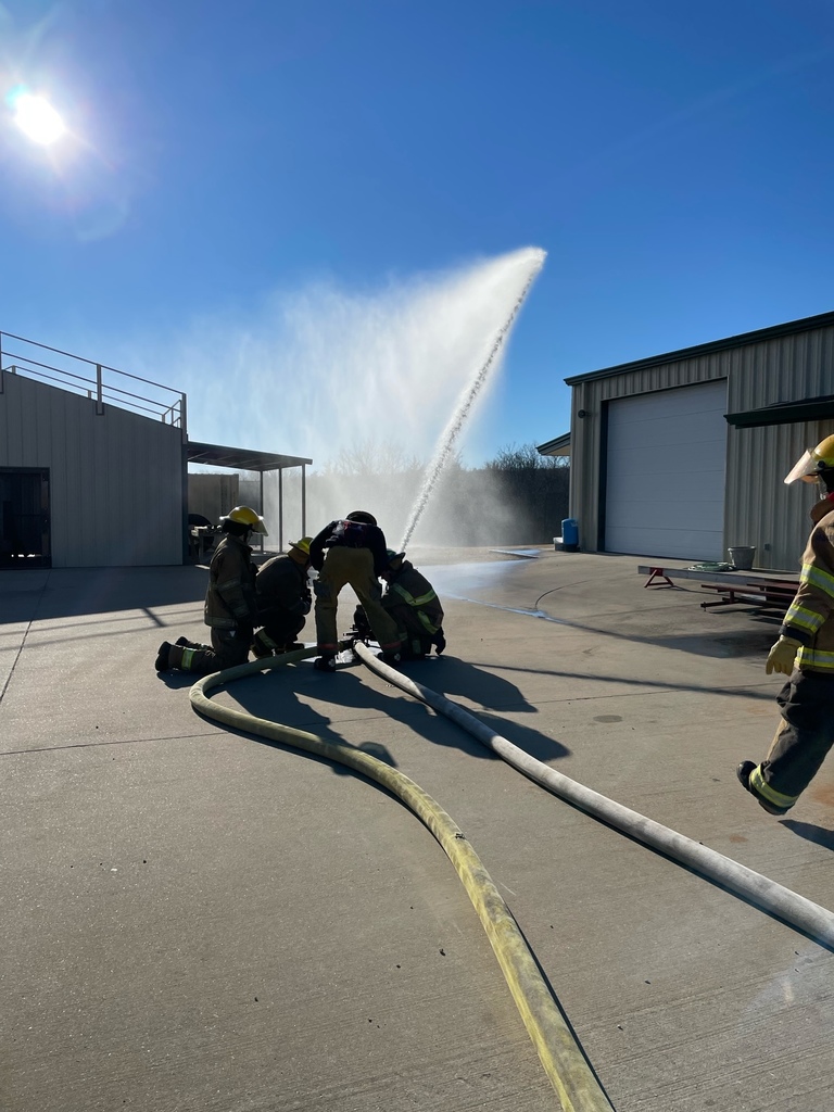 Image of students learning to use a fire hose.