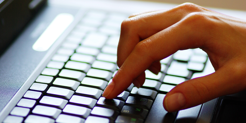 Picture of a hand typing on a laptop keyboard