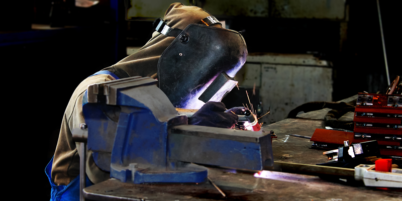 Picture of a welder welding with protective helmet on