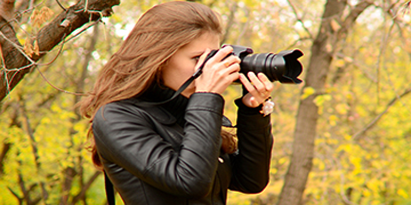 Picture of a woman taking a photo with a camera with a zoom lens