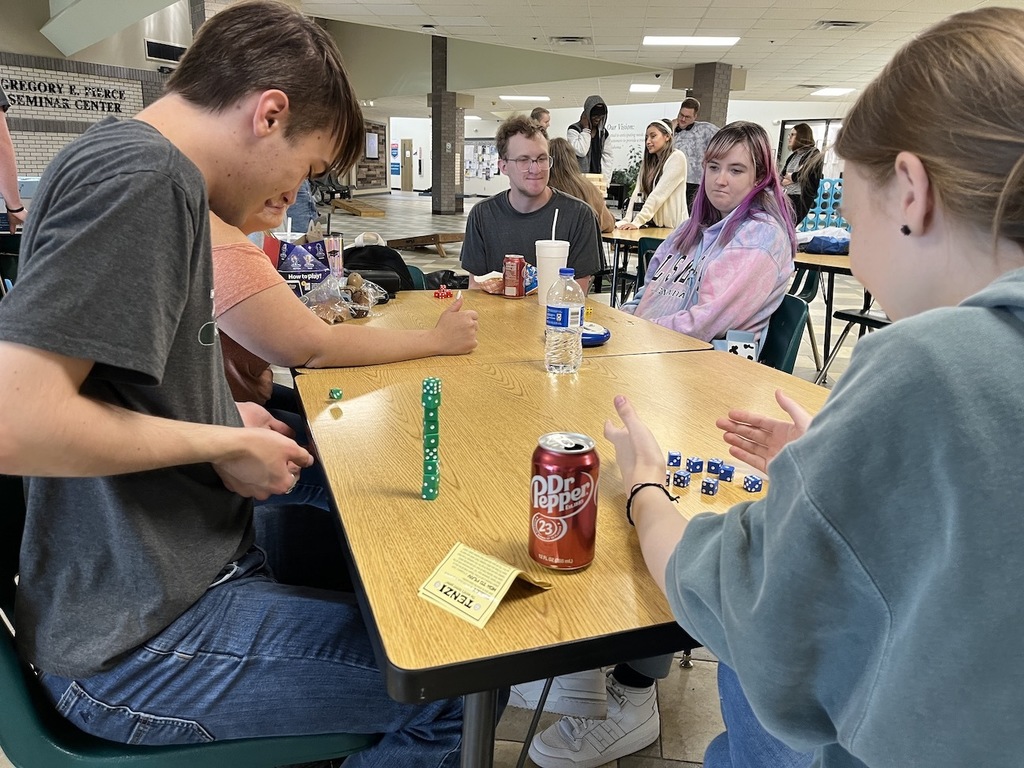 Several students sitting around a table playing dice games