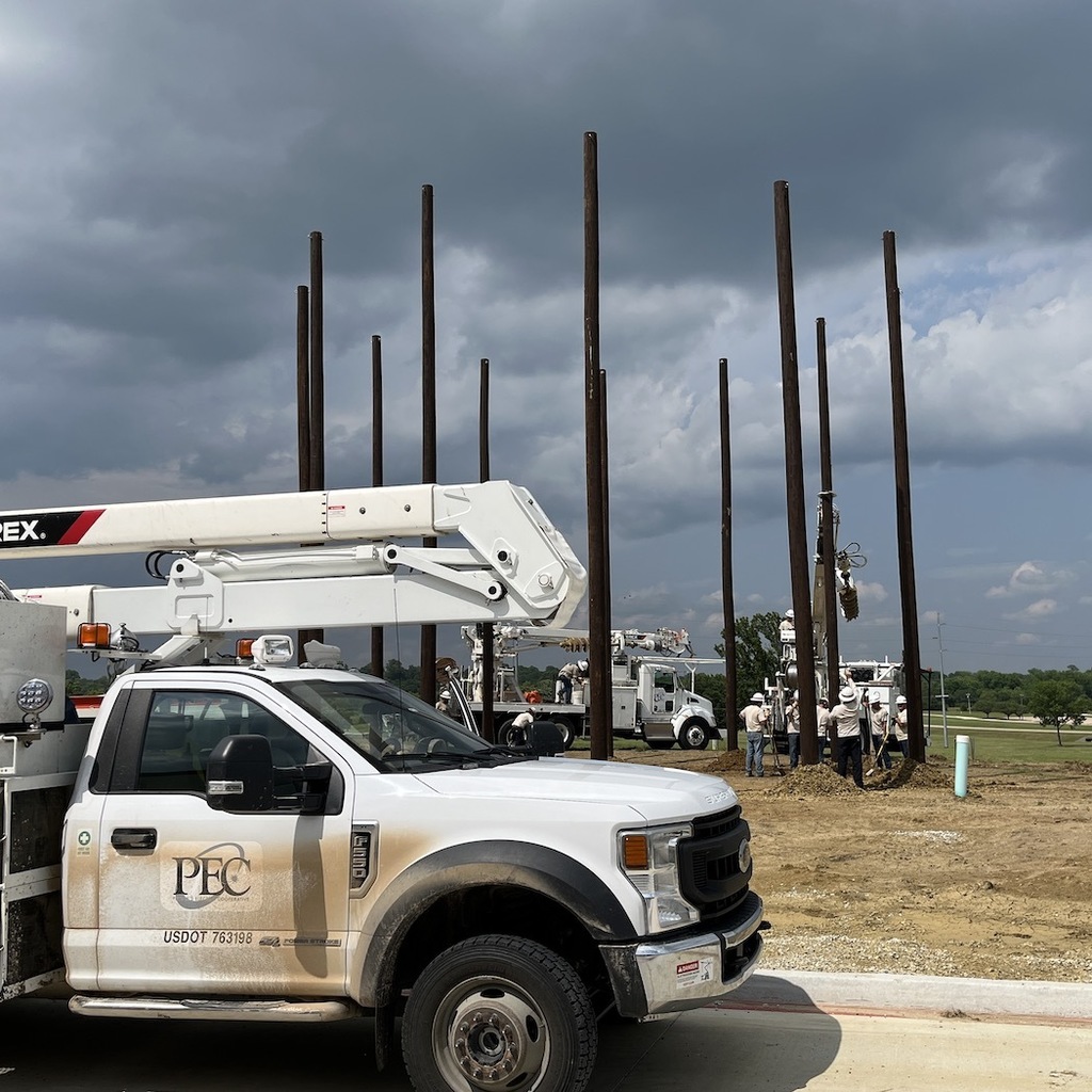 PEC truck in the foreground, the new pole yard with 12 poles installed in a circle behind it